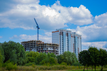 Fototapeta na wymiar modern construction building process with crane near two tall houses in clean ecology park outdoor natural scenic environment 