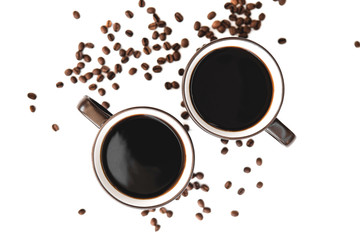 two large mugs of dark color with light walls and dark inside brewed coffee, standing on a light table where chaotically scattered roasted coffee beans