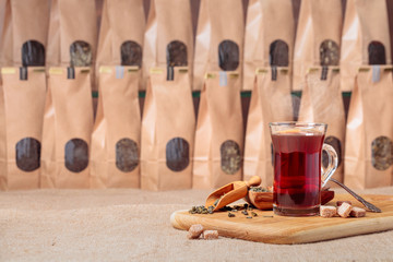 Glass of hot tea and wooden spoon with dried tea leaves.