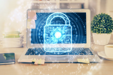 Double exposure of desktop with computer and lock icon hologram. Concept of data safety.