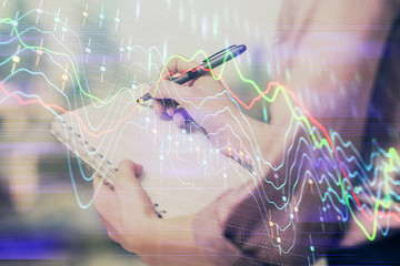 Multi exposure of hands making notes with forex chart huds. Stock market concept.