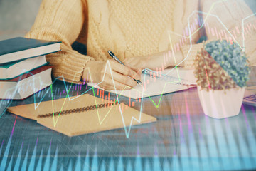 Forex graph on hand taking notes background. Concept of research. Double exposure