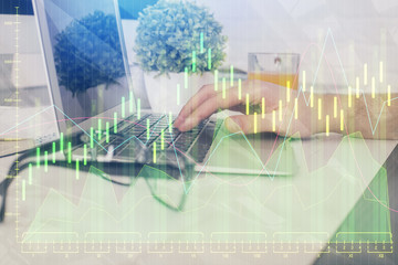 Multi exposure of graph with man typing on computer in office on background. Concept of hard work....