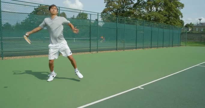 A mixed race tennis player runs across the baseline, volleys and celebrates.