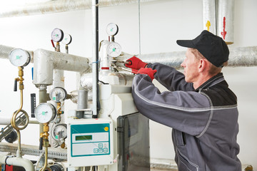 heating engineer or plumber in boiler room installing or adjusting manometer