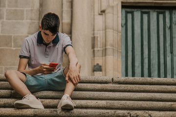 young teenage man with mobile phone in the city outdoors