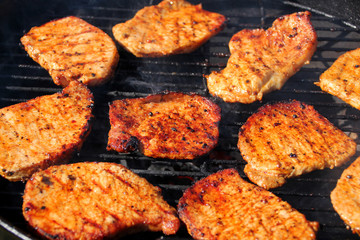beautiful grilled roasted meat steaks grilled on the street on a black metal grill on burning coals, picnic concept, close-up