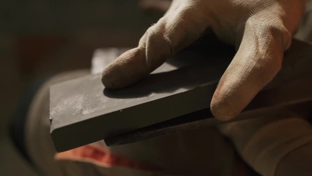 hands of a man who is sharpening an ax blade
