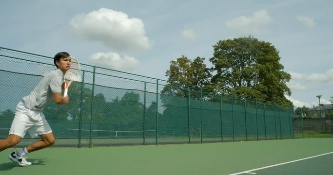 A mixed race tennis player volley a shot and celebrates in slow motion.