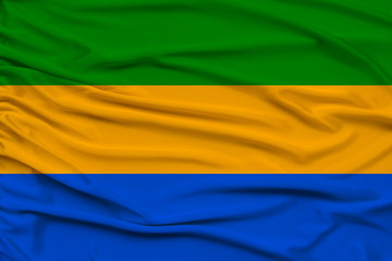 beautiful photo of the national flag of Gabon on delicate shiny silk with soft draperies, the concept of state power, country life, horizontal, close-up, copy space