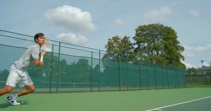 A mixed race tennis player volley a shot and celebrates in slow motion.