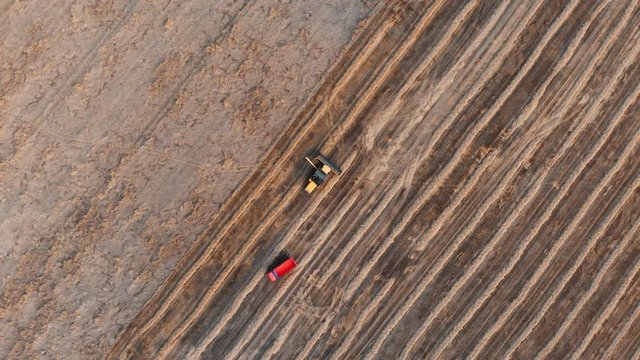 red truck drives to big black and orange cropper for loading