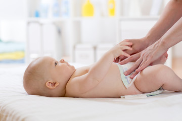 Obraz na płótnie Canvas Mother changes her baby nappy in nursery