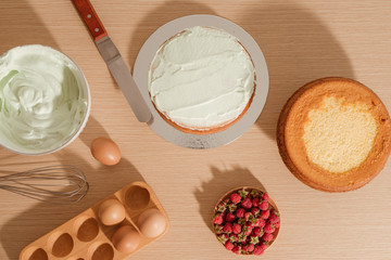 Simple sponge cake with powdered sugar and fresh raspberries on wood background. Summer berry dessert.