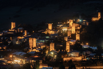 Fototapeta na wymiar Night view on Mestia with its beautiful illuminated Svan Towers and high mountains. Svaneti, Georgia.