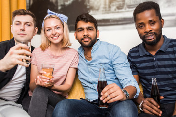 Cheerful multi-ethnic friends sitting on sofa