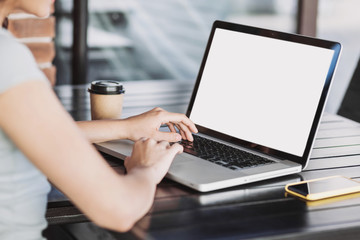 Young woman using laptop outdoor. Student girl working at cafe. Blank white empty device screen...