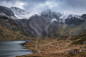 Naklejka na ściany i meble Beautiful moody Winter landscape image of Llyn Idwal and snowcapped Glyders Mountain Range in Snowdonia