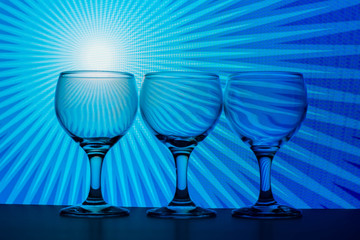 Three empty glass cups with a bright blue background 