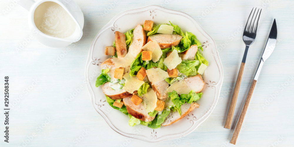 Wall mural A panorama of a chicken Caesar salad, shot from above with a sauce boat and a place for text