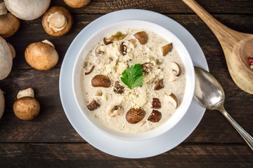 Mushroom soup, shot from the top with ingredients on a dark rustic wooden background