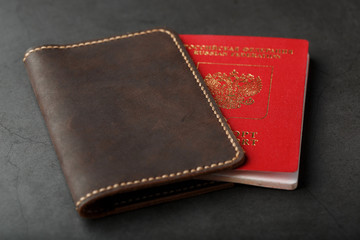 Brown leather cover with a red passport on a dark background