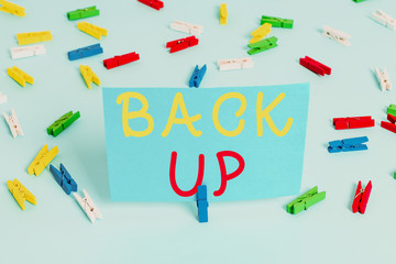 Handwriting text Back Up. Conceptual photo saving important data into internet cloud and restore them later Colored clothespin papers empty reminder blue floor background office pin