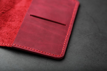 Red leather cover for a passport on a dark background. Genuine leather, handmade, close up stitching