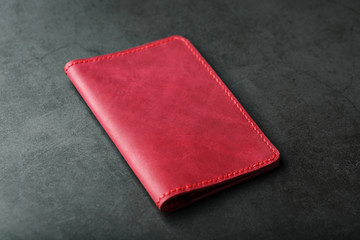 Red leather cover for a passport on a dark background. Genuine leather, handmade, close up stitching