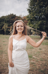 young charming woman in a white sundress laughs and plays with her blond hair, life style
