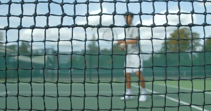 A Tennis player volleys the ball hard into the net.