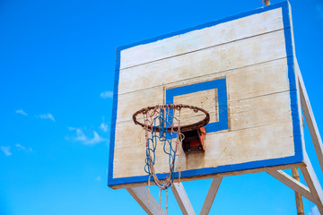 Basketball backboard on blue sky background. Rustic outdoor sport equipment. Summer outdoor activity concept.