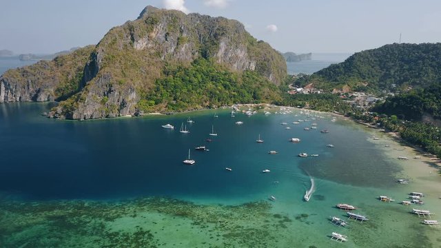 4k drone footage of tropical Corong corong beach, El Nido, Palawan, Philippines. Calm tranquil morning, traditional boats and small yachts resting on blue water. Summer and travel vacation concept