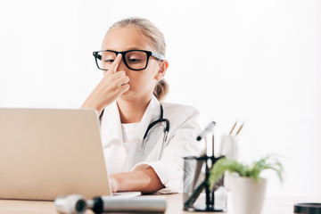 child in doctor costume using laptop in clinic