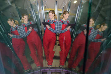 female worker holding tablet seen in reflected mirror images