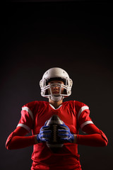 Photo of American woman football player in helmet with rugby ball in her hands on blank black background