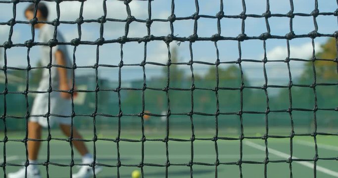 A Tennis player mis hits the net, throws his racket and kicks the air in frustration.