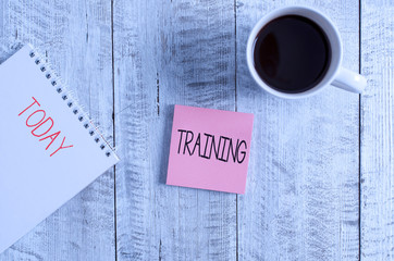 Conceptual hand writing showing Training. Concept meaning An activity occurred when starting a new job project or work Stationary placed next to a coffee cup above wooden table