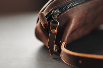 Handmade genuine brown leather on a dark background Brown belt bag. Elegant brown bag with a zipper © Alexander