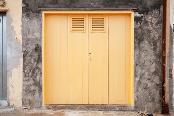 Closed old yellow gate in grungy stone wall