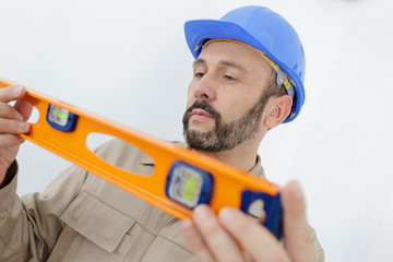 a male builder measuring a wall