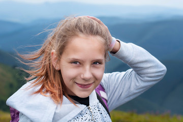 Portrait of a young girl resting in the mountains, though she is tired but happy because she has...