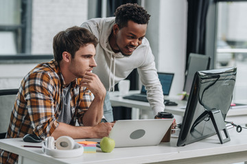 two serious multicultural programmers working in office together
