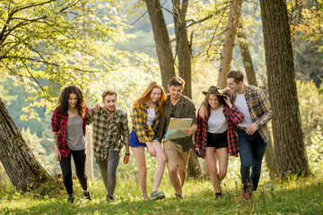 positive young tourists walking with a map in the forest, full length photo. travel, adventure, people