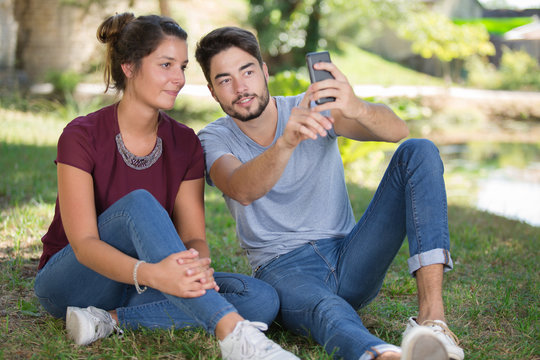 Couple sat on grass taking a selfie