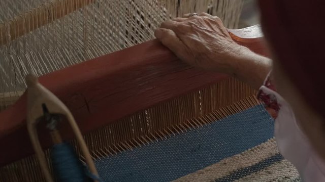 weaver makes fabric in ethnic loom