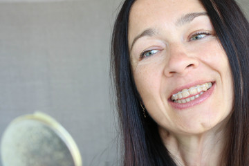 Close up portrait of  smiling woman with orthodontic elastic chain on teeth looking at mirror