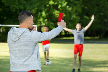 referee hands with red card on football field