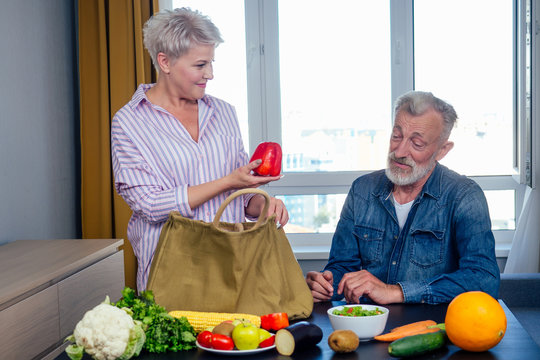 happy elderly man and woman unpacking fruit and peper from cotton eco bag - Powered by Adobe