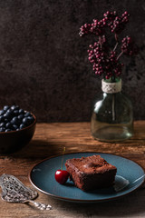 Freshly baked homemade vegan chocolate brownie served with a cherry and blueberries